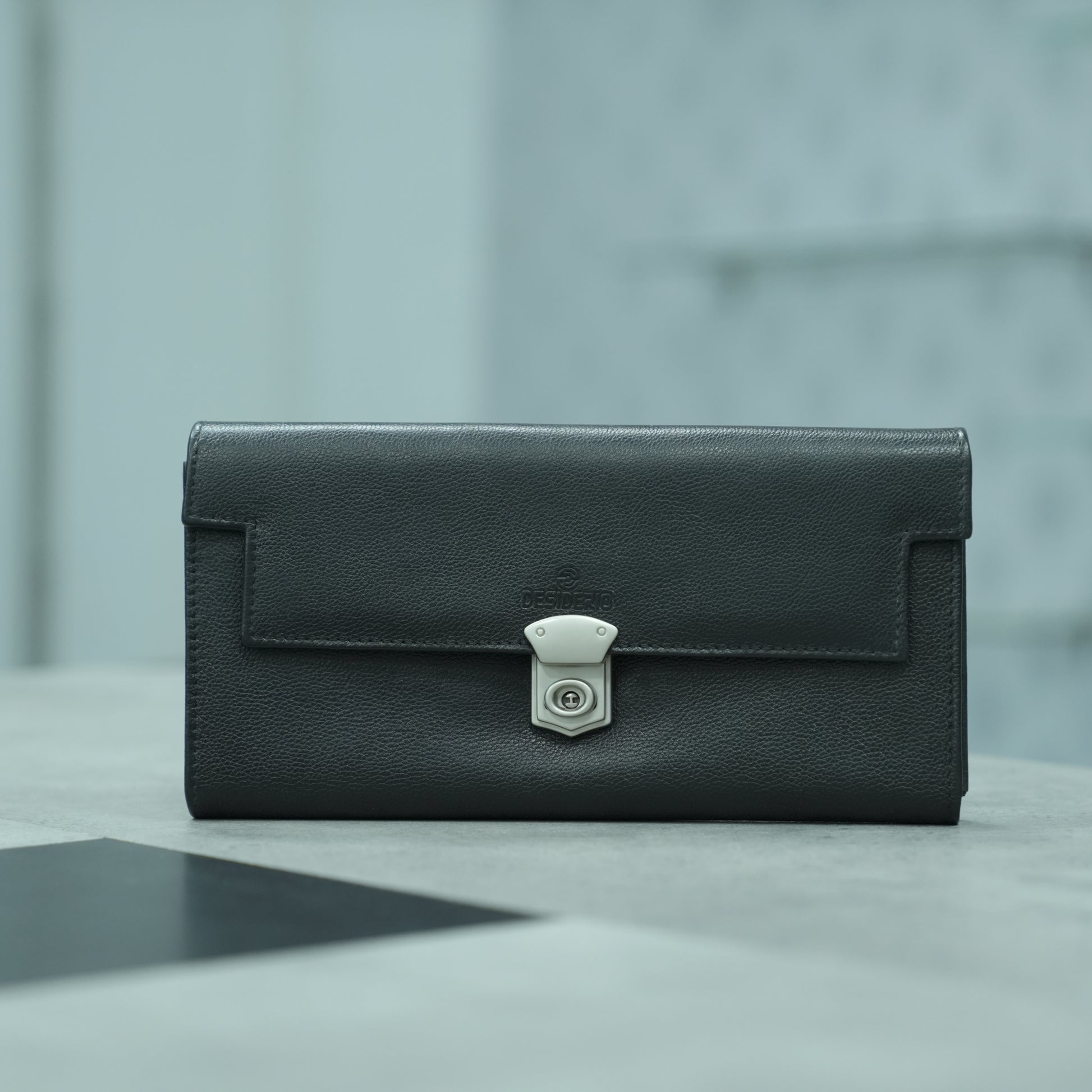 Black leather clutch with three compartments, sixteen card slots, a zip pocket, cash compartment, and key for security