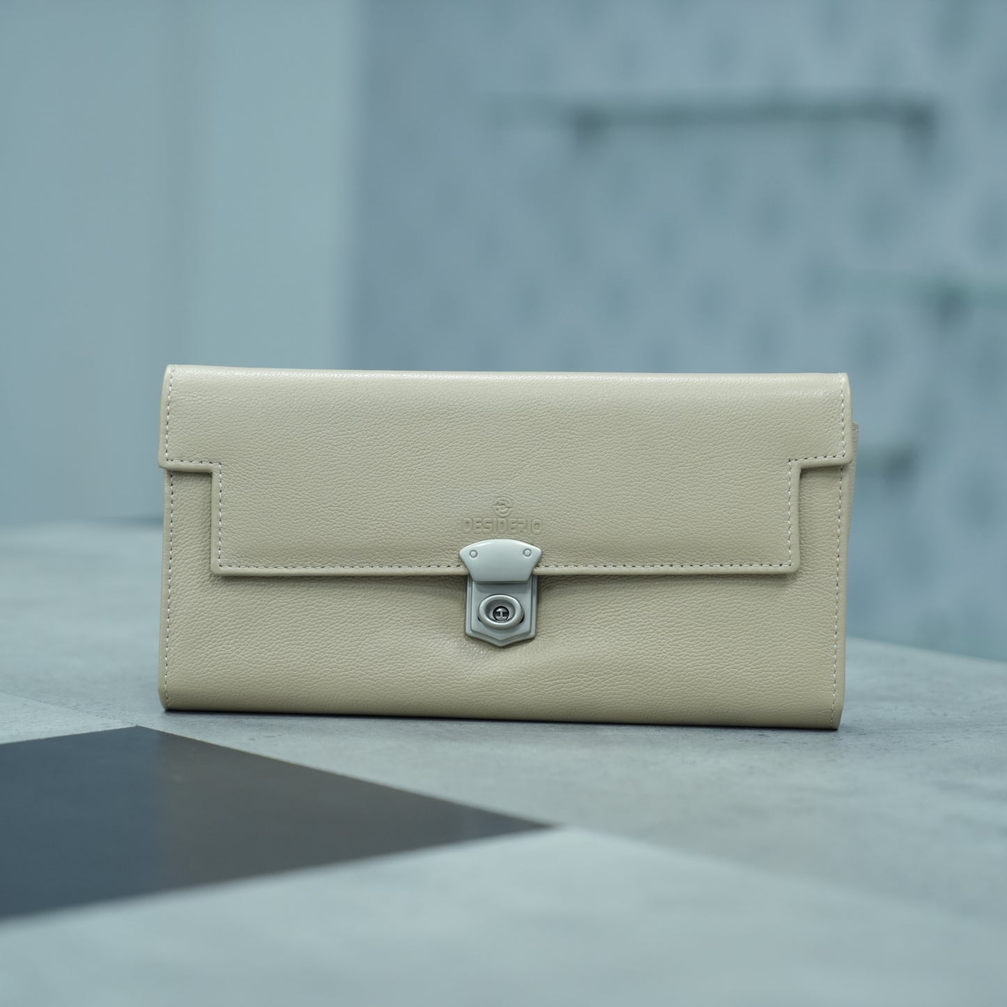 Beige leather clutch with three compartments, sixteen card slots, one zip pocket, cash compartment, and key for security