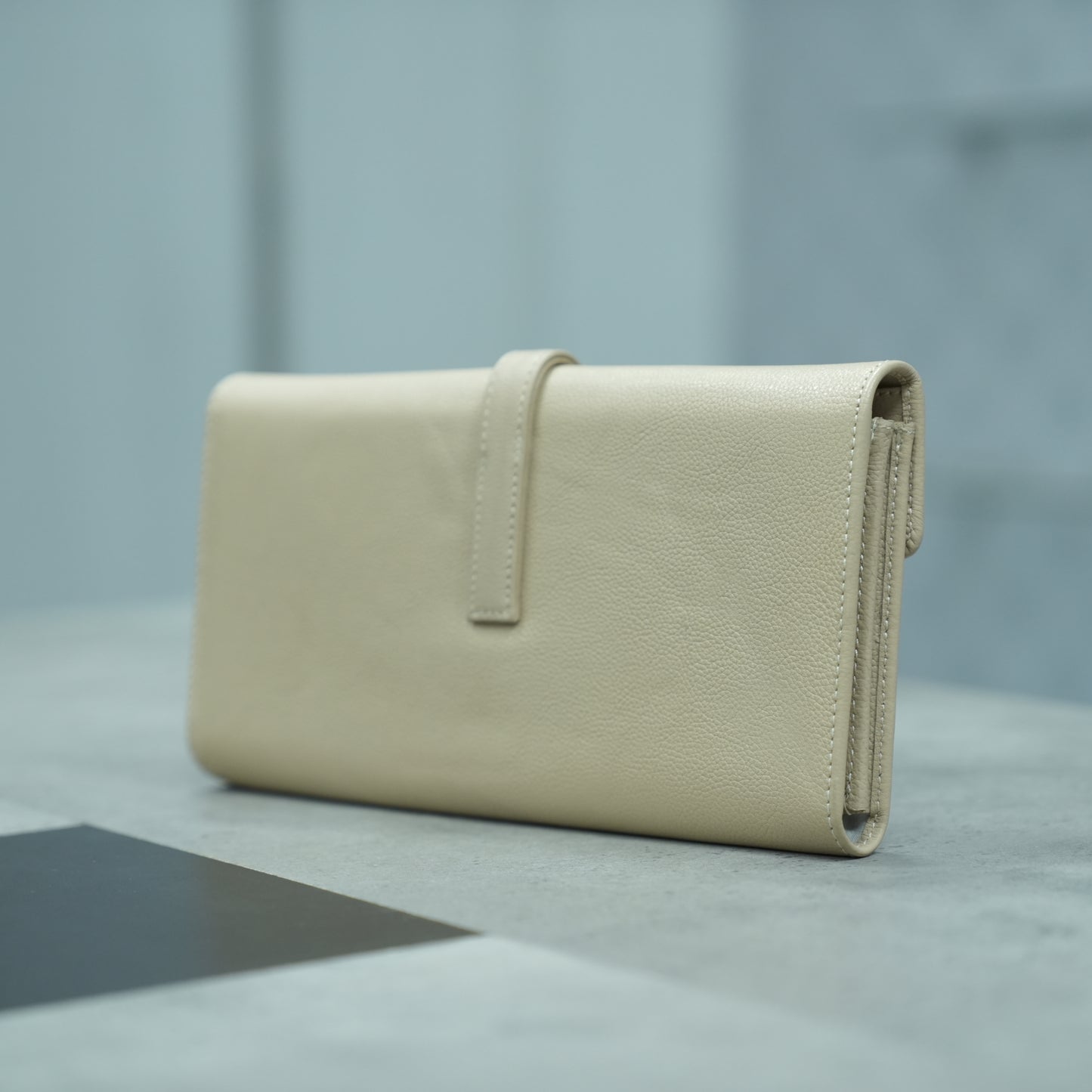 Beige leather mini clutch with three compartments, sixteen card slots, and a zip pocket