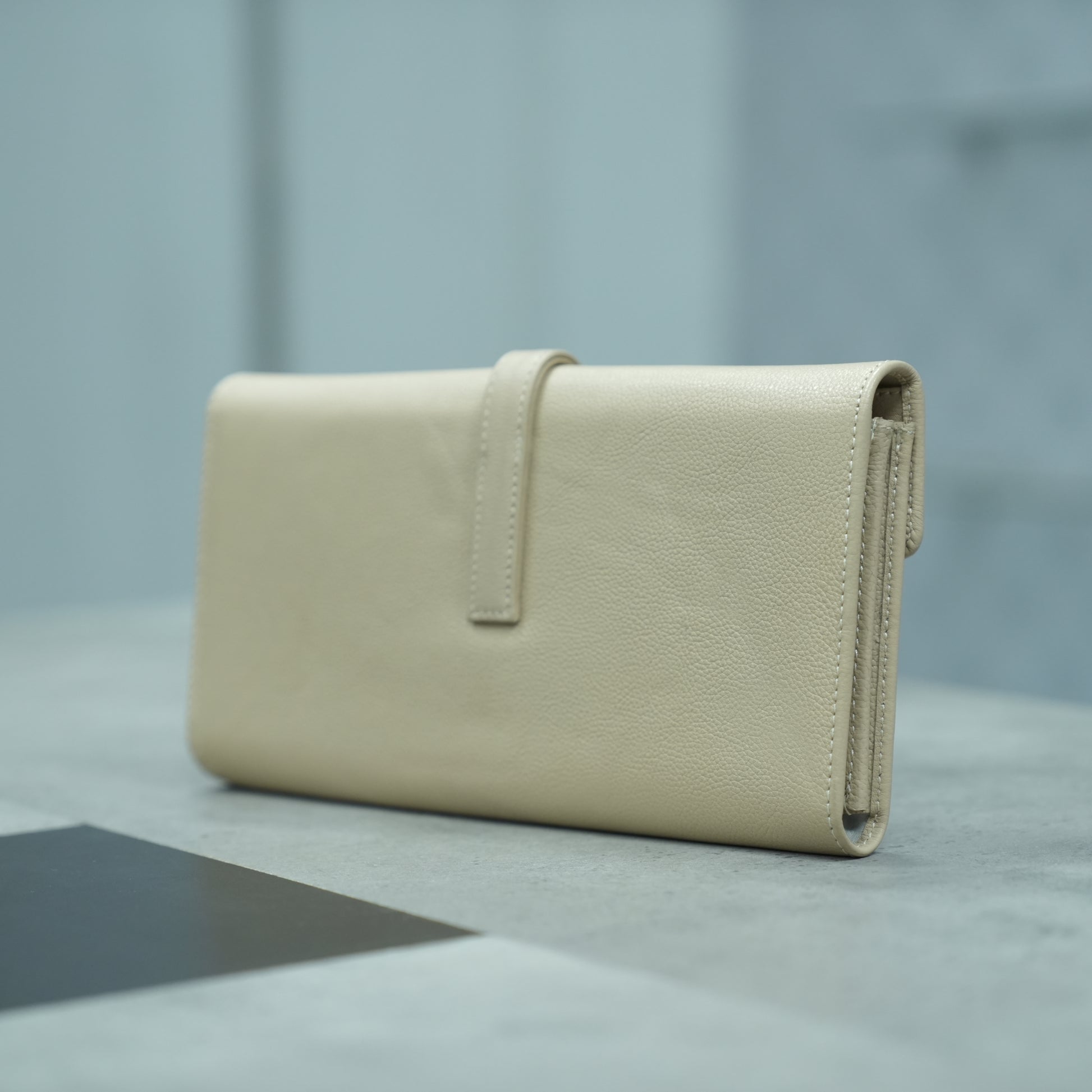 Beige leather mini clutch with three compartments, sixteen card slots, and a zip pocket