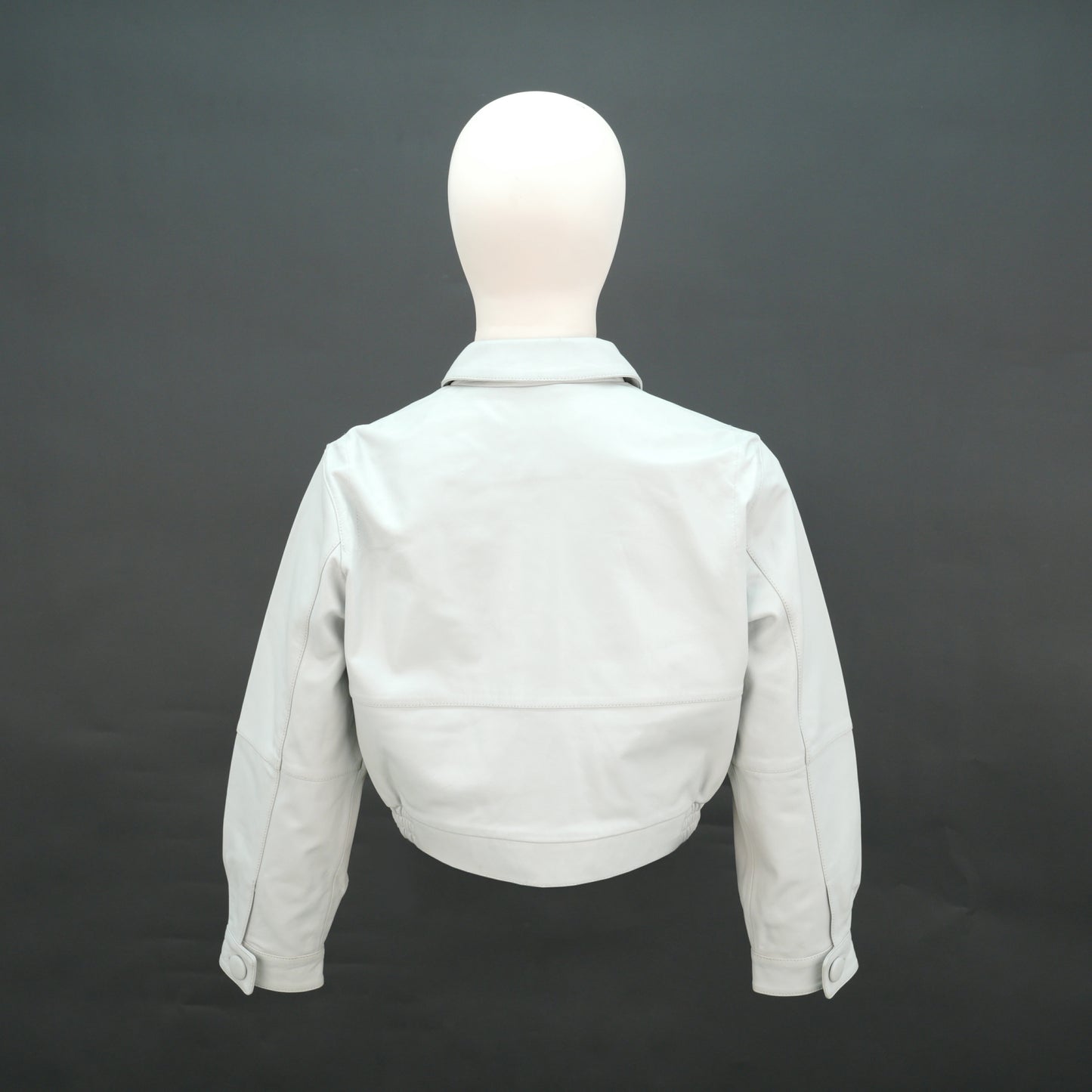 White cropped leather jacket with shirt collar and flap pockets.