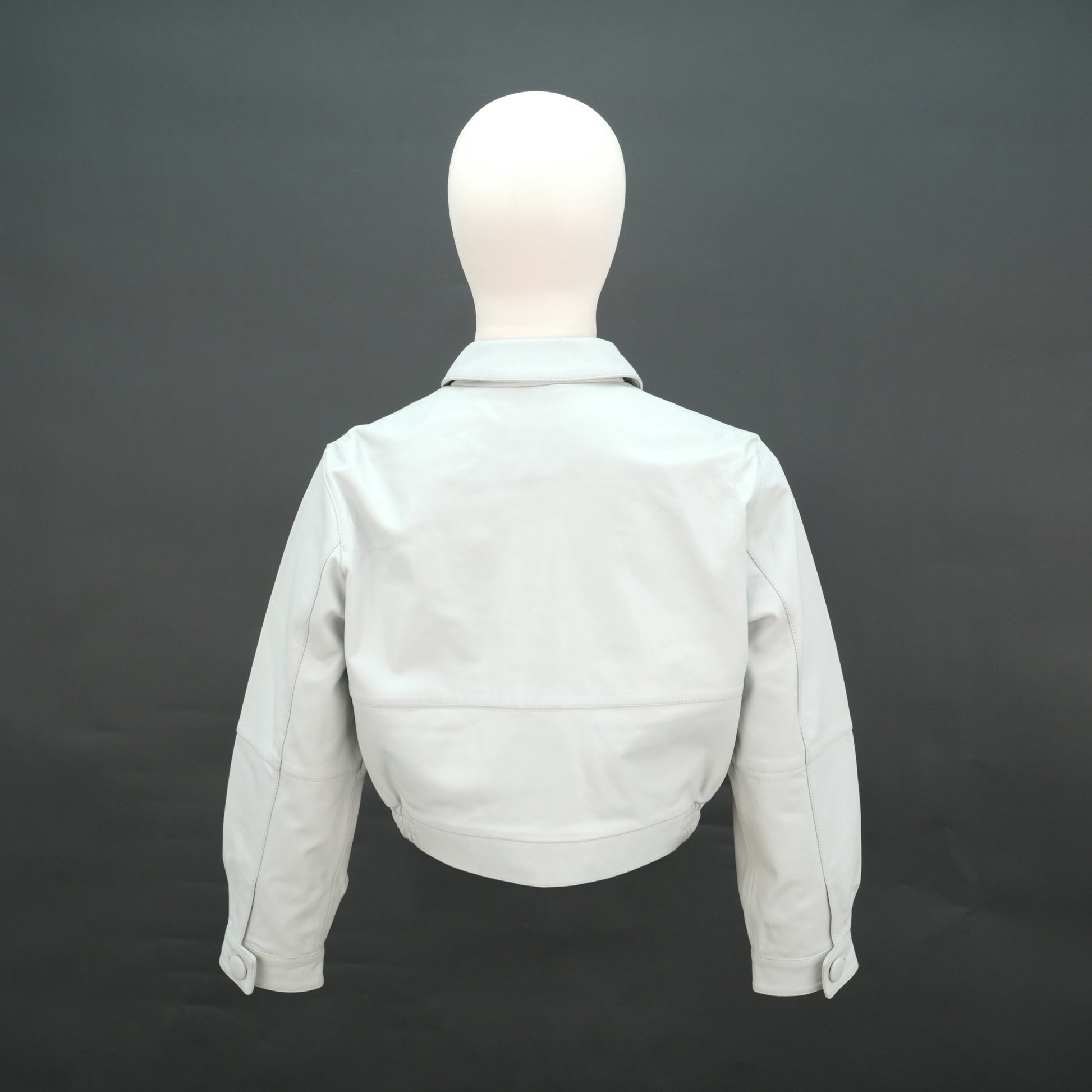 White cropped leather jacket with shirt collar and flap pockets.