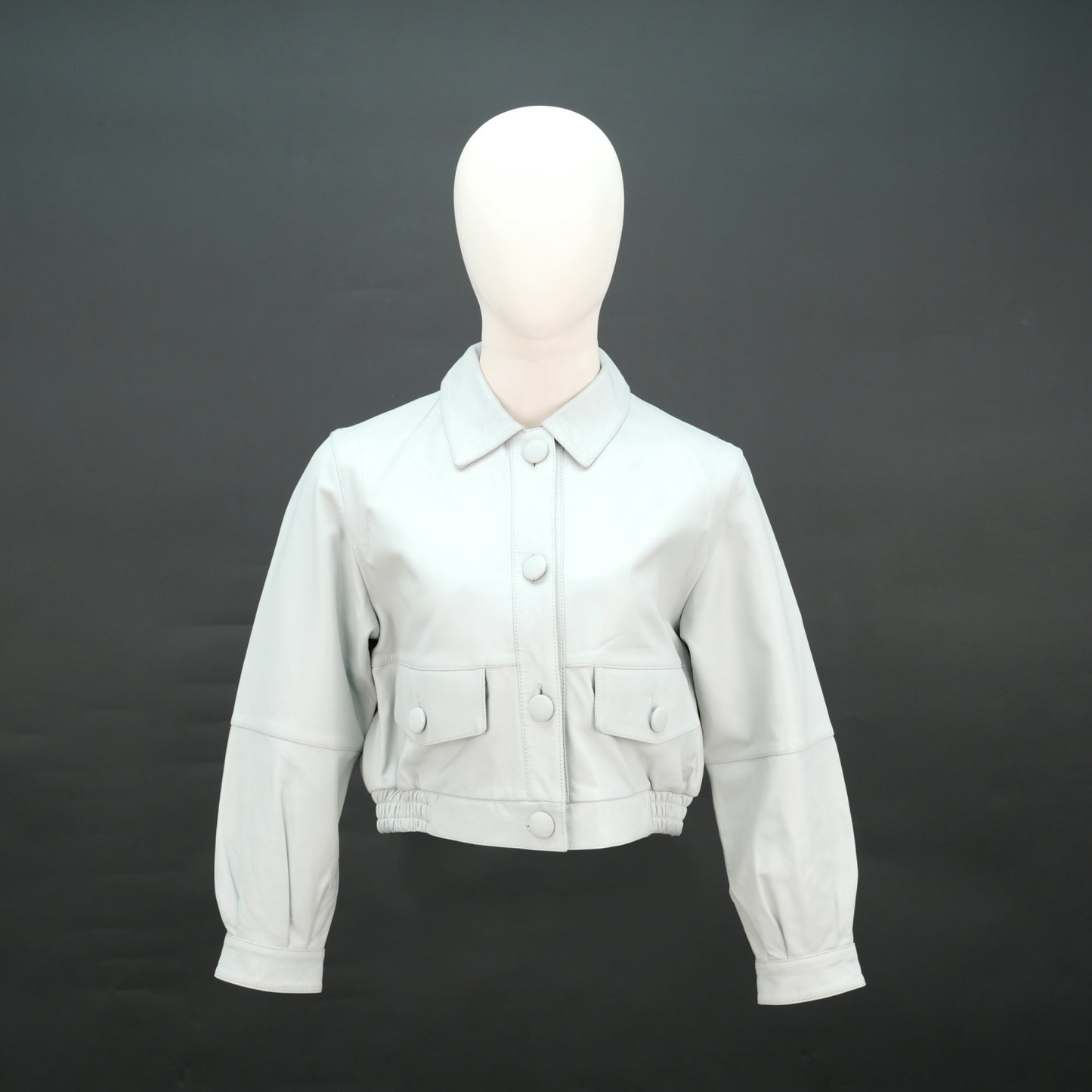 White cropped leather jacket with shirt collar and flap pockets.
