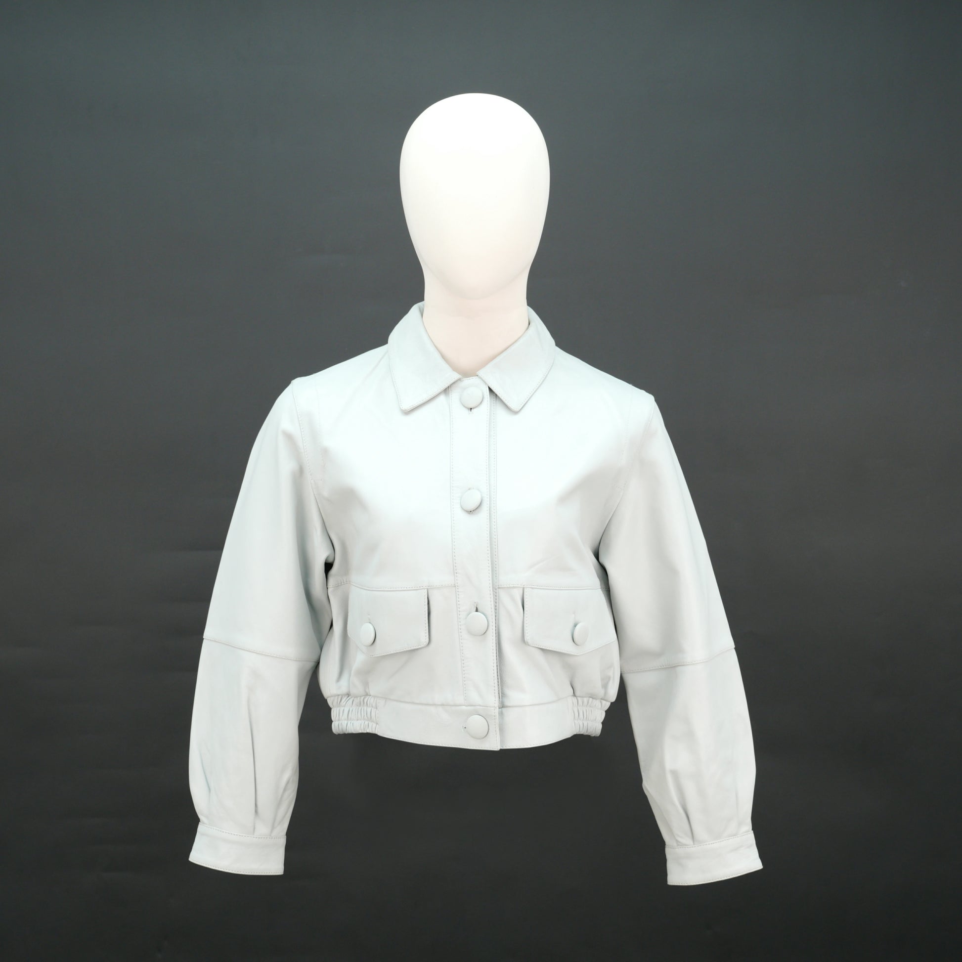 White cropped leather jacket with shirt collar and flap pockets.